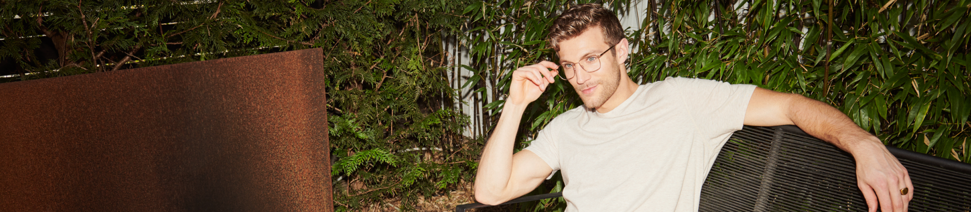 Man in glasses and shirt sitting down on outdoor couch