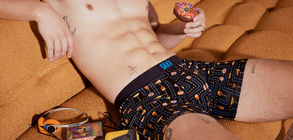 An image of a man's torso sitting on a leather couch wearing a pair of boxer briefs in a video game print.