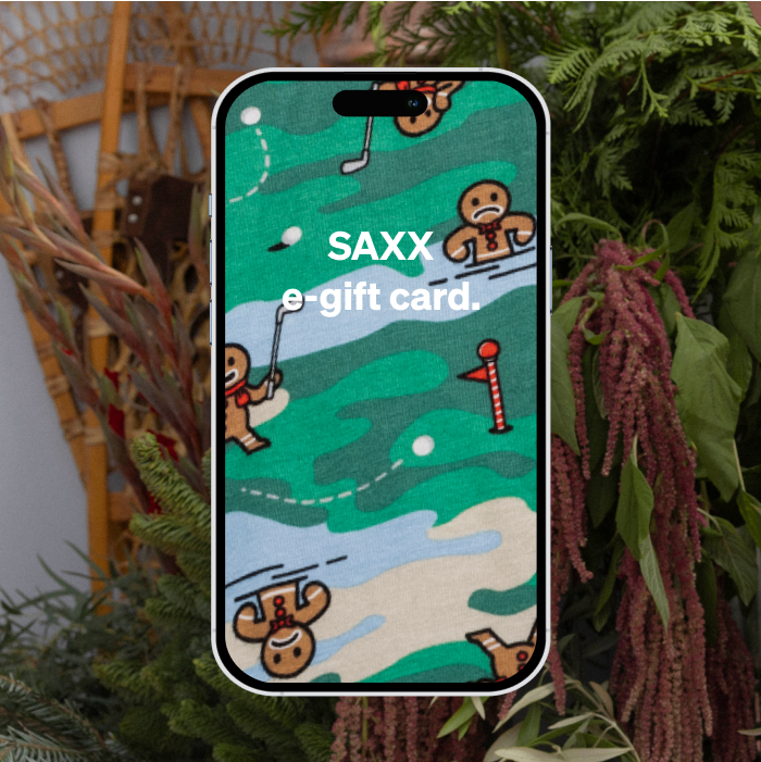 A phone screen with green camo print and gingerbread men playing golf, reading “SAXX e-gift card” with winter greenery in back.