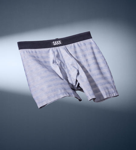 A pair of light-grey tonal-striped boxer briefs with a black waistband floating against a dar grey background.