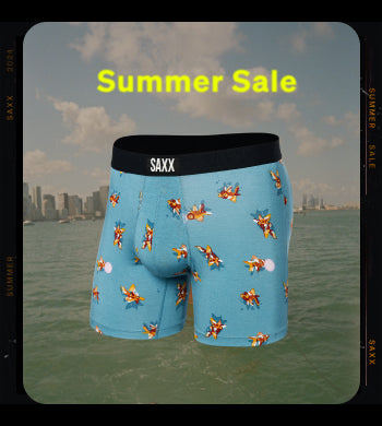 A snapshot of the ocean with a city skyline visible in the distance, a pair of blue SAXX boxer briefs with goldfish pattern overlaying the image along with the text "Summer Sale".  