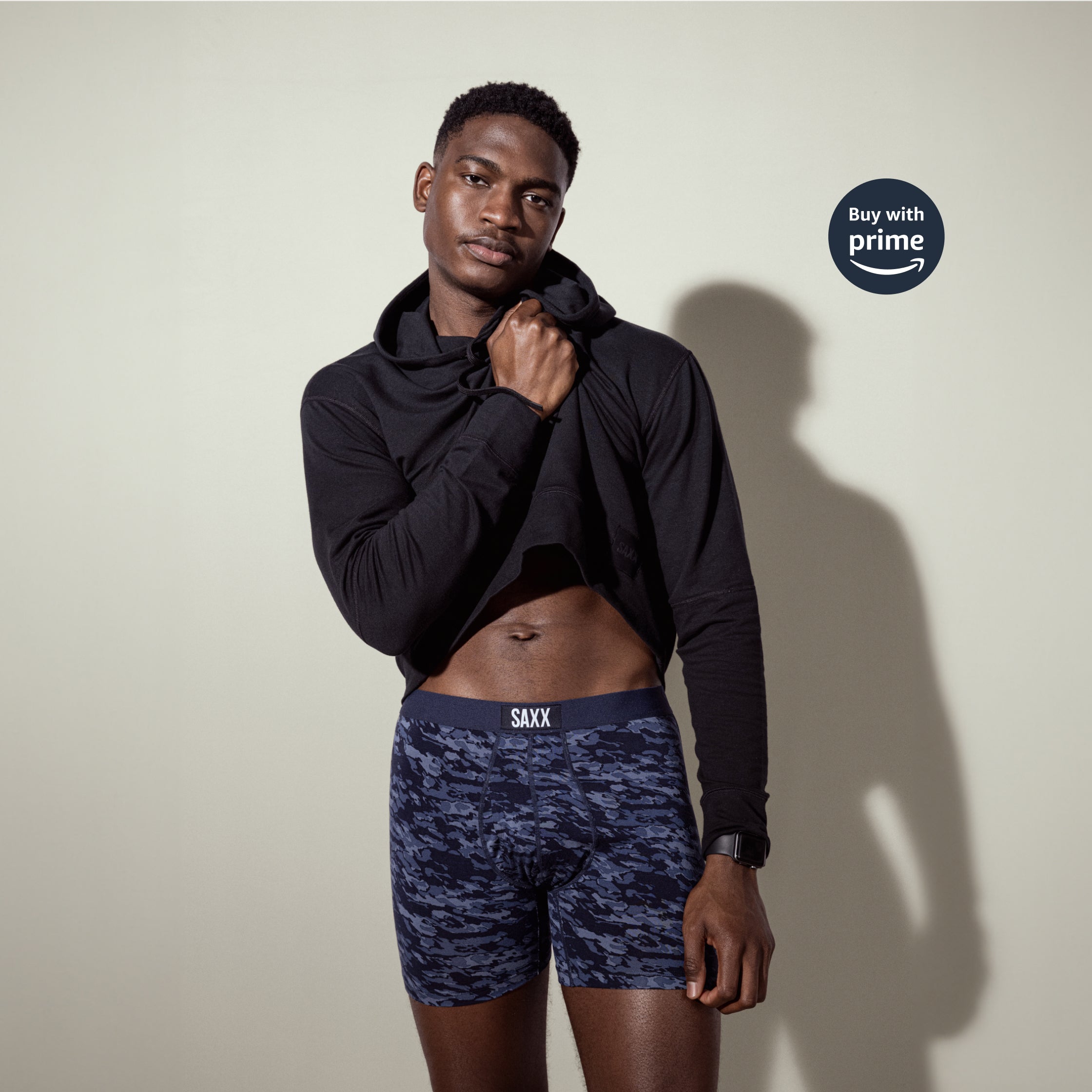 Man in black hoodie and dark blue underwear lifting top to expose mid section