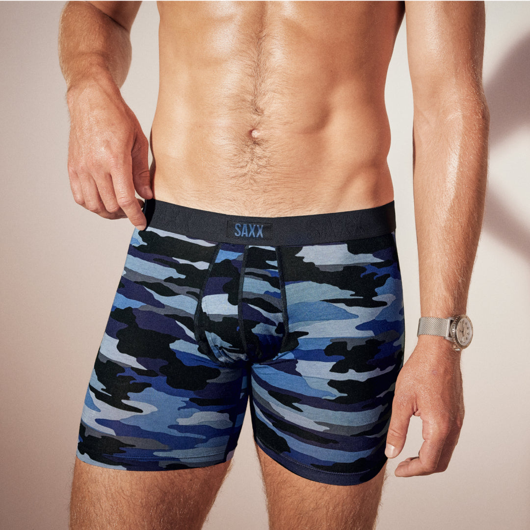 A close up of a man’s underwear in blue camouflage print he has his right hand at his right hip. 